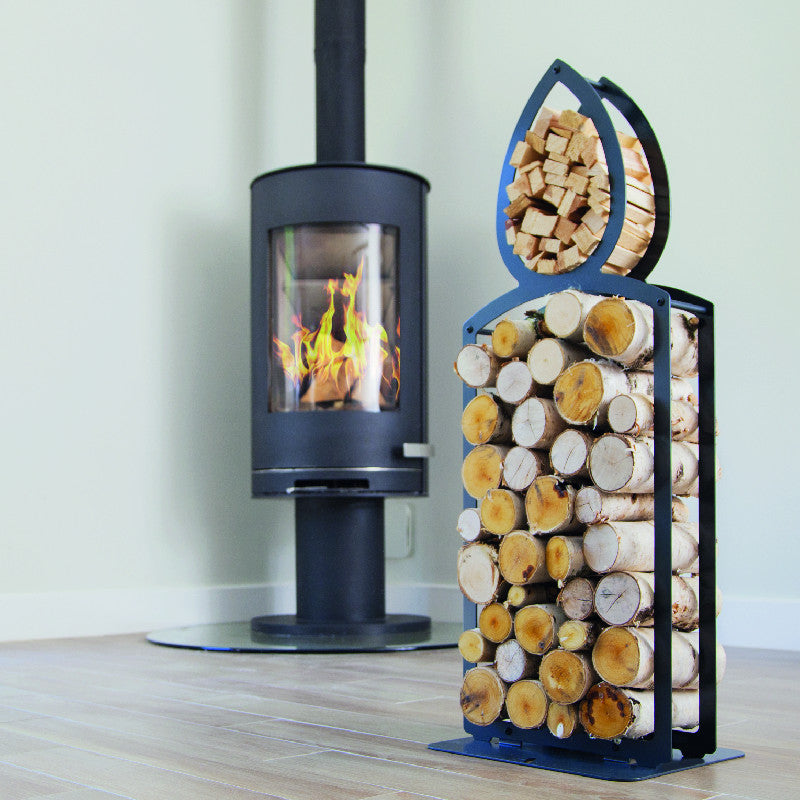 One of Ardour's candle shaped metal log baskets in jet black. It is a tall candle shape with two compartments; A small one at the top to store kindling and a large one for the main body to store the logs. Its compact design means logs can be stored in a smaller foot print than a traditional wicker basket of a similar footprint
