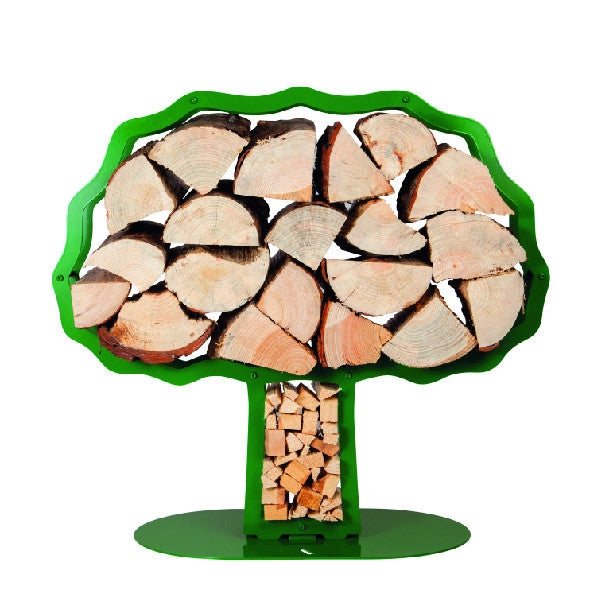 One of Ardour's Oak tree shaped metal log baskets in may-green next to a modern fire. It has a profile of an oak tree with a broad trunk and is attached to a base-plate. The design has two compartments; one in the trunk to store kindling and a large one for the main body of the tree to store the logs. 